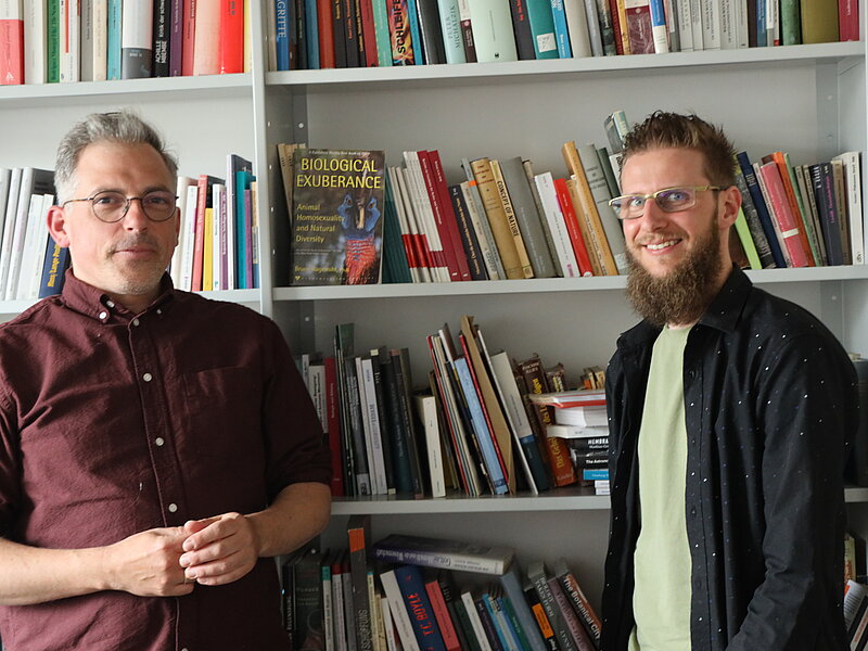 Zwei Männer vor einem Bücherregal