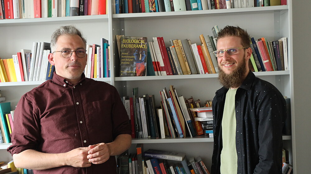 Zwei Männer vor einem Bücherregal