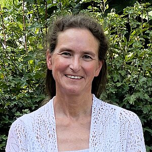 Lächelnde Frau in weißer Bluse.