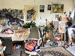 Im Malerei-Atelier: viele Bilder an den Wänden und auf dem Boden an die Wand gelehnt
